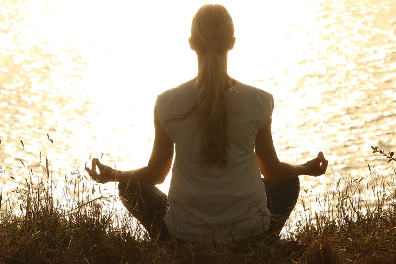 Woman practicing yoga and meditation at sunset